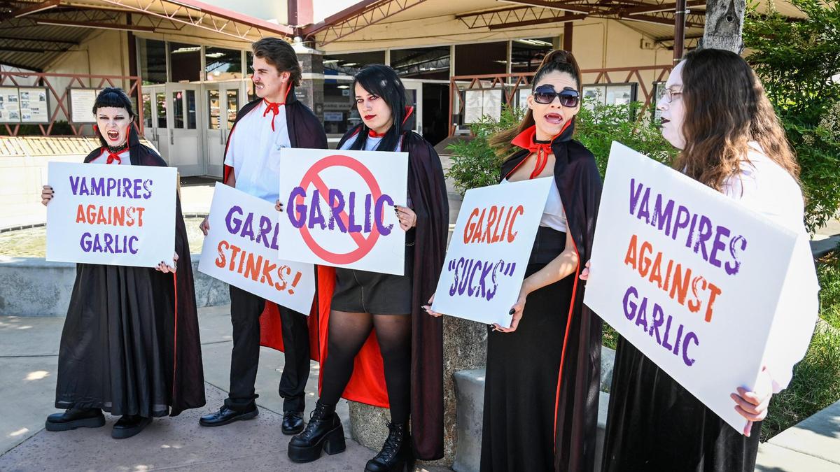 A group of entertainers dressed as vampires hold a mock protest against garlic, considered to be a vampire deterrent, on day one of the National Garlic Festival at the Fresno Fairgrounds on Friday, May 13, 2022.