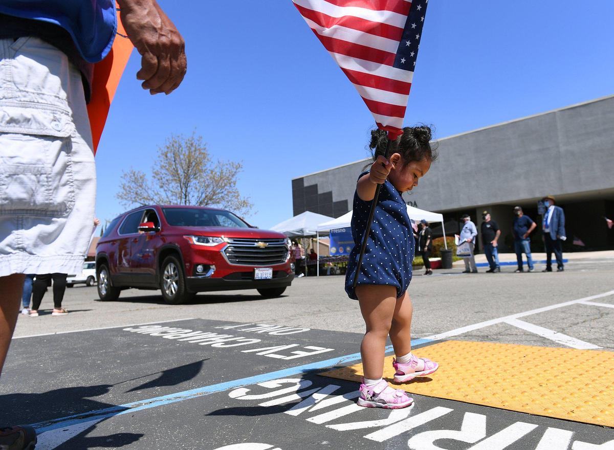 Scarlett Murphy, age 20 months, keeps her flag flying high even while distracted at a drive through ceremony honoring service men and women in observance of National Vietnam War Veterans Day on Monday afternoon, March 29, 2021, at the Fresno Vet Center at Shaw Avenue and Sixth Street.