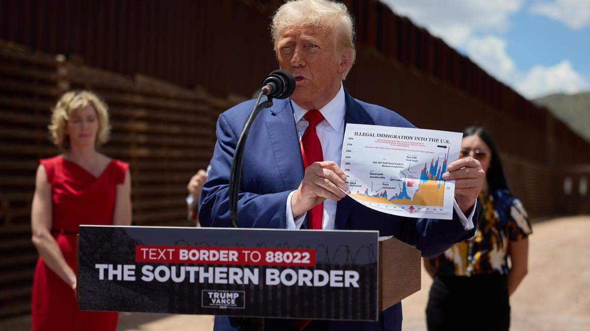 El expresidente y candidato presidencial republicano Donald J. Trump sostiene un gráfico de cifras de inmigración mientras habla durante su visita a la frontera sur de Estados Unidos en el condado de Cochise, Arizona, el 22 de agosto. / Former President and Republican presidential nominee Donald J. Trump holds up an immigration numbers graph as he speaks during his visit to the US southern border in Cochise County, Arizona on Aug. 22.
