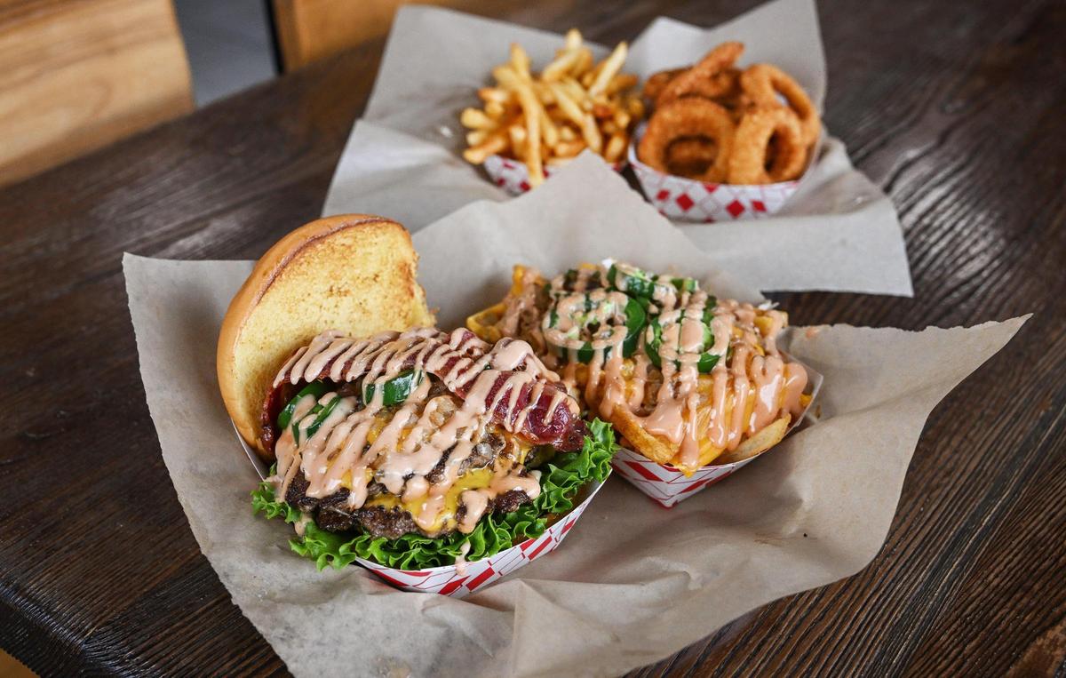 “The Main,” front left, Main Street Burgers’ signature burger, and street fries are pictured with onion rings and Cajun fries.