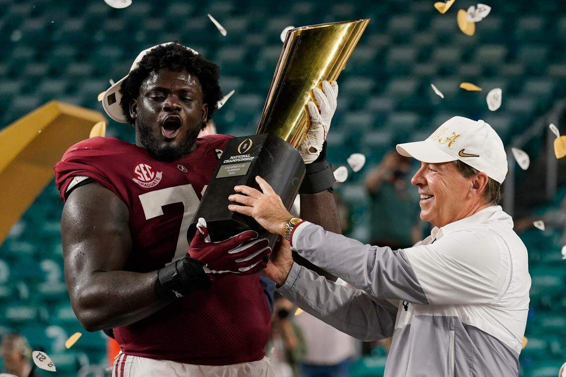 Alabama head coach Nick Saban and offensive lineman Alex Leatherwood hold the trophy after their win against Ohio State in the NCAA College Football Playoff national championship game Jan. 12, 2021, in Miami Gardens, Fla. Alabama won 52-24.