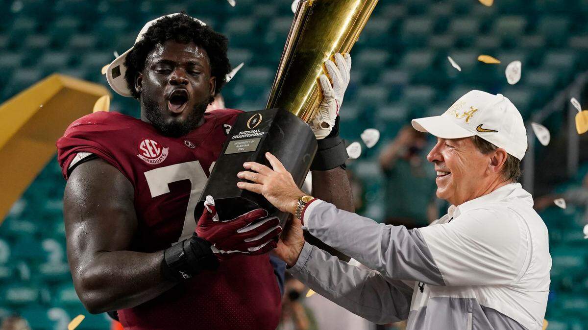 Alabama head coach Nick Saban and offensive lineman Alex Leatherwood hold the trophy after their win against Ohio State in an NCAA College Football Playoff national championship game, Tuesday, Jan. 12, 2021, in Miami Gardens, Fla. Alabama won 52-24. (AP Photo/Lynne Sladky)