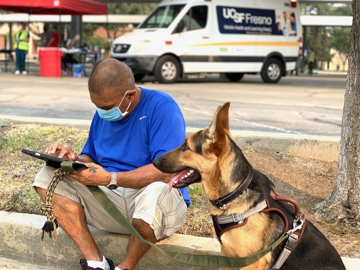With his dog by his side, a man completes a COVID-19 testing registration form. UCSF Fresno’s COVID-19 Equity Project leans heavily on community-based organizations to make those who use the project’s services feel at ease.
