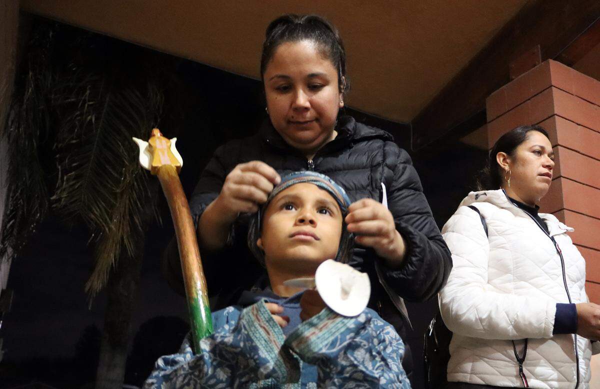 A mother adjusts a head dressing for her child who took part in the posada hosted by St. Anthony Mary Claret Church in southeast Fresno on Dec. 18, 2023.