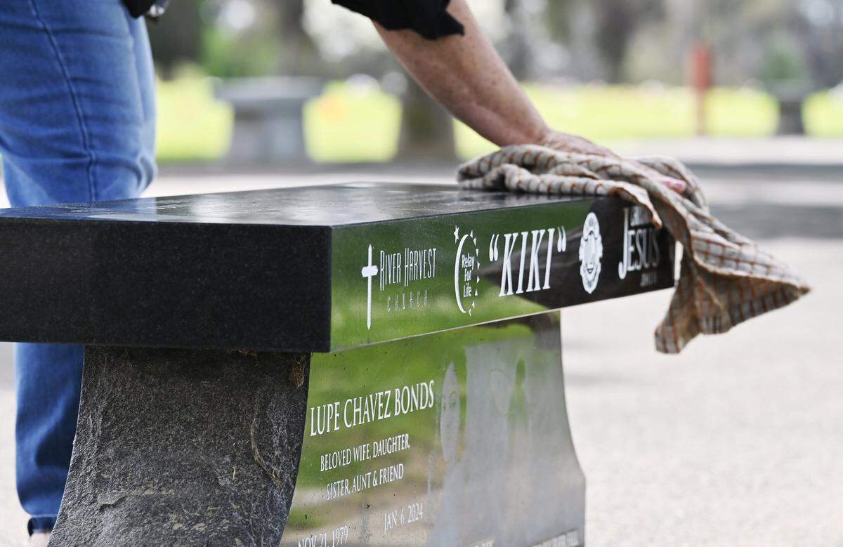 Susan Grote cleans the bench dedicated to her daughter-in-law Guadalupe “Kiki” Bonds, located at Reedley Cemetery District Tuesday, May 26, 2026 in Reedley. Four family members including Grote's son Mathew Bonds were found killed in January 2024. Grote is still waiting for a transfer hearing for the teen charged in the homicides.