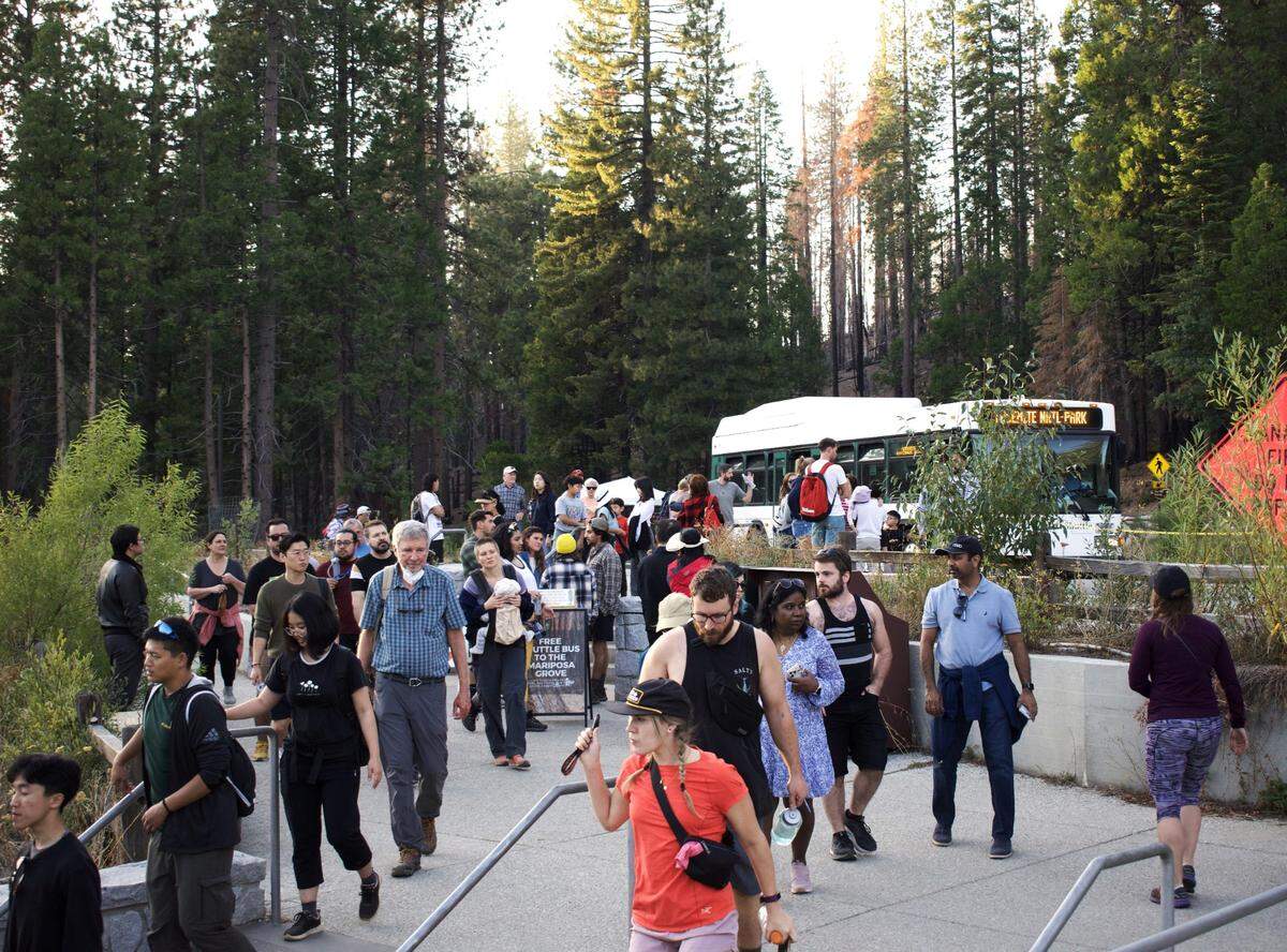 Dozens of tourists step out of a shuttle bus just inside Yosemite National Park’s south entrance Monday evening. A partial closure of the park could mean services, along with facilities, would not be available to visitors.