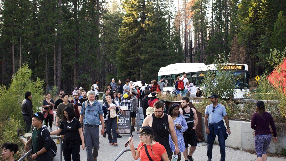 Dozens of tourists step out of a shuttle bus just inside Yosemite National Park