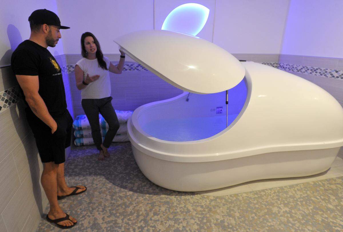 True REST Float Spa owner Kelly Clay shows client Tomas Mundarain one of the floatation pods.