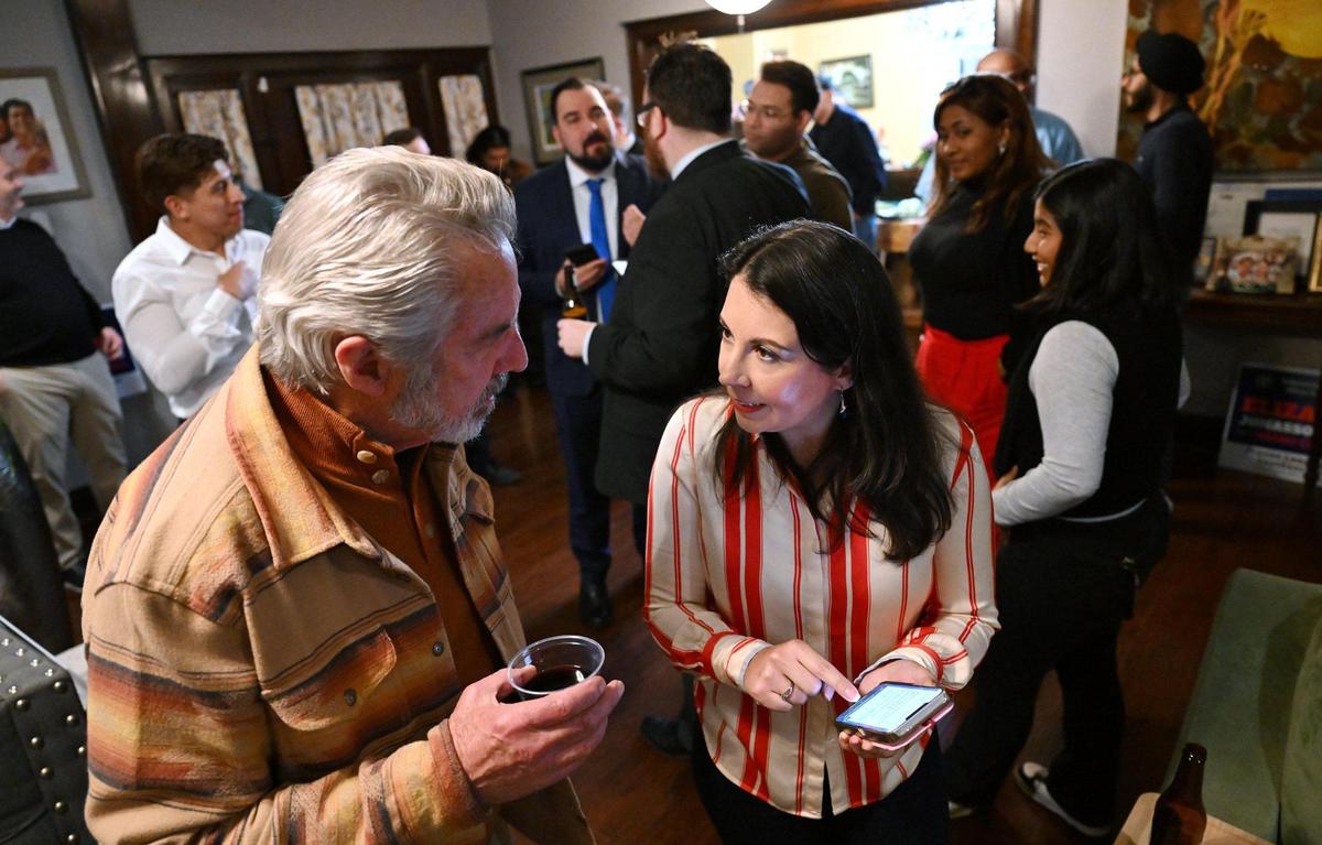 Family member Mark Parode, left, leans in as Fresno City Council District 5 candidate Elizabeth Jonasson Rosas, right, checks for the first online results of the special runoff election Tuesday night, March 18, 2025 in Fresno.