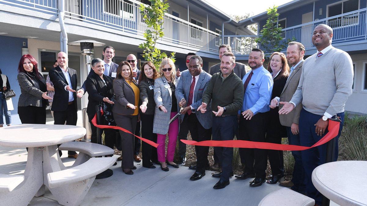 Tyrone Rodrick Williams, CEO of Fresno Housing Authority, center, cuts the ribbon surrounded by guests an dignitaries for Fresno County Department of Behavior Health and partners’ new The Villages at Paragon, a renovated multi-unit structure designed as safe and healthy affordable housing Wednesday, Nov. 17, 2021 in Fresno.