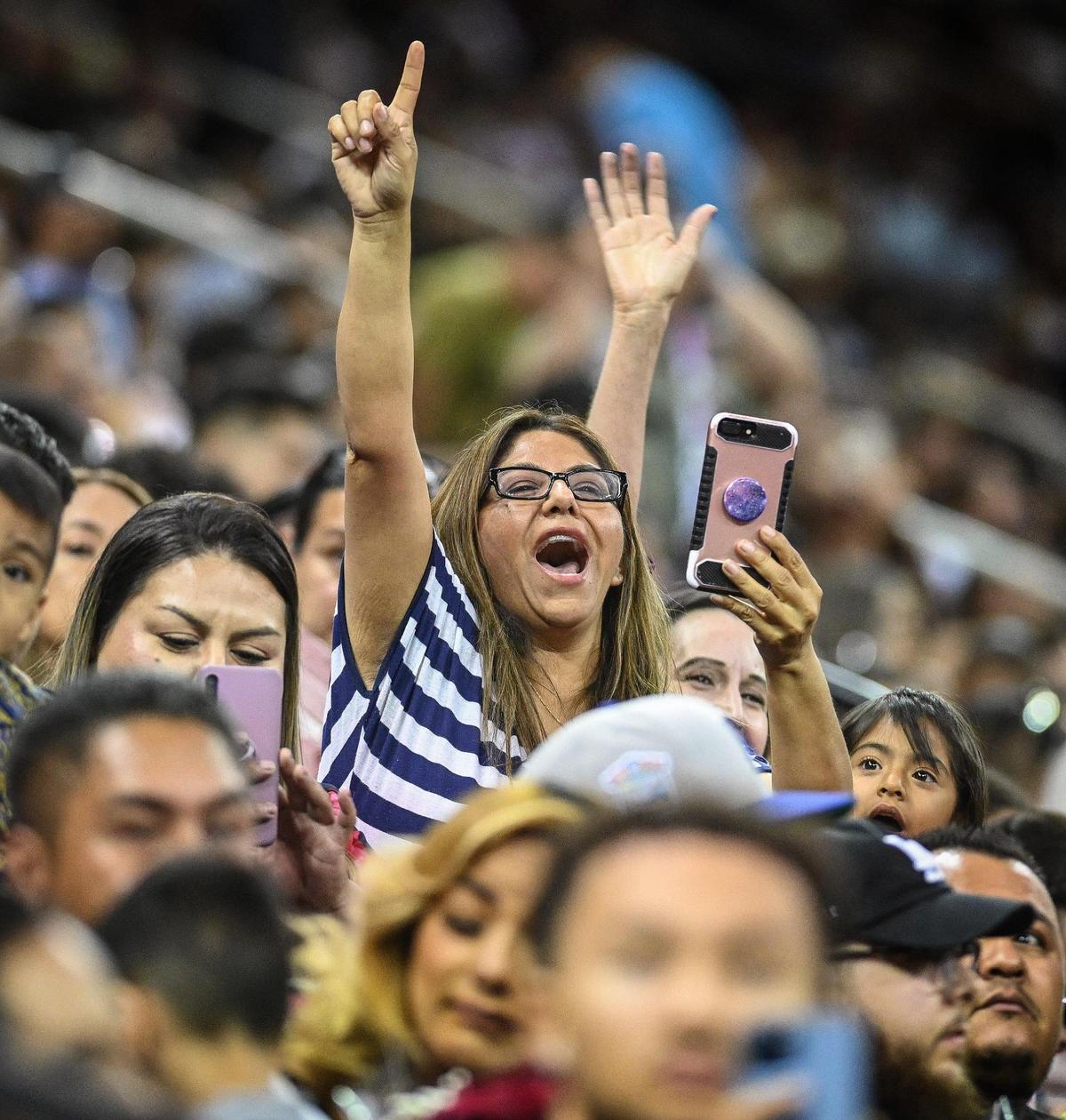 Family and friends cheer and take photos from the stands during the 46th annual Fresno State Chicano/Latino Commencement Ceremony held at the Save Mart Center on Saturday, May 21, 2022.