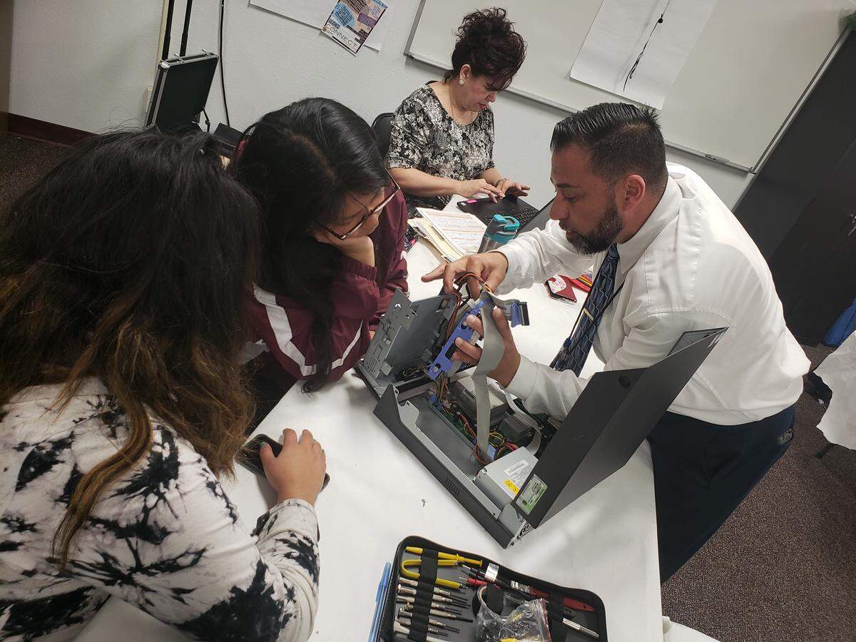 TECH Connect director Miguel Castaneda shows students how to take apart computers and put them back together to prepare them for possibly repairing computers for community members.