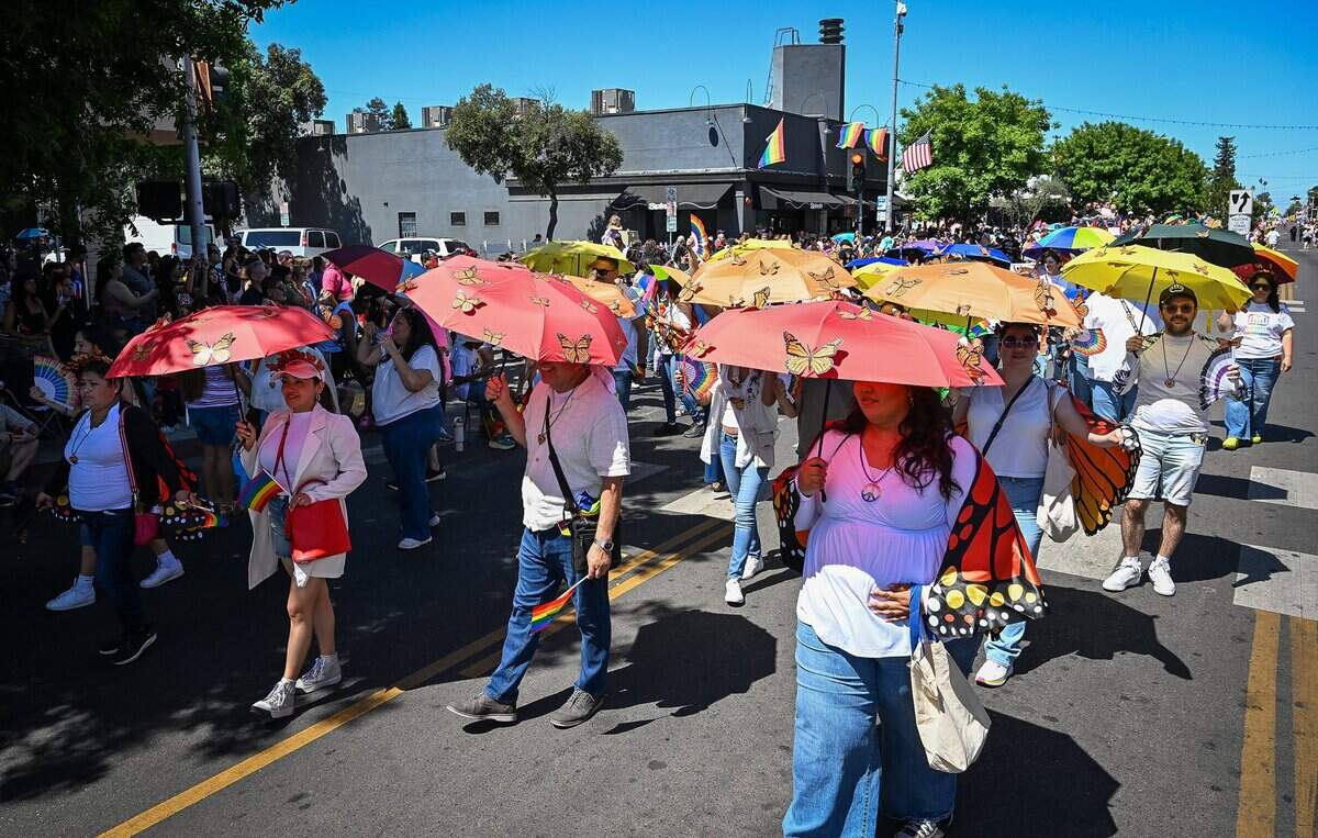Parade participants carrying butterfly covered umbrellas walk with others from the Consulate of Mexico in Fresno and local community partners during the annual Fresno Rainbow Pride Parade and Festival in the Tower District on Saturday, June 6, 2026.