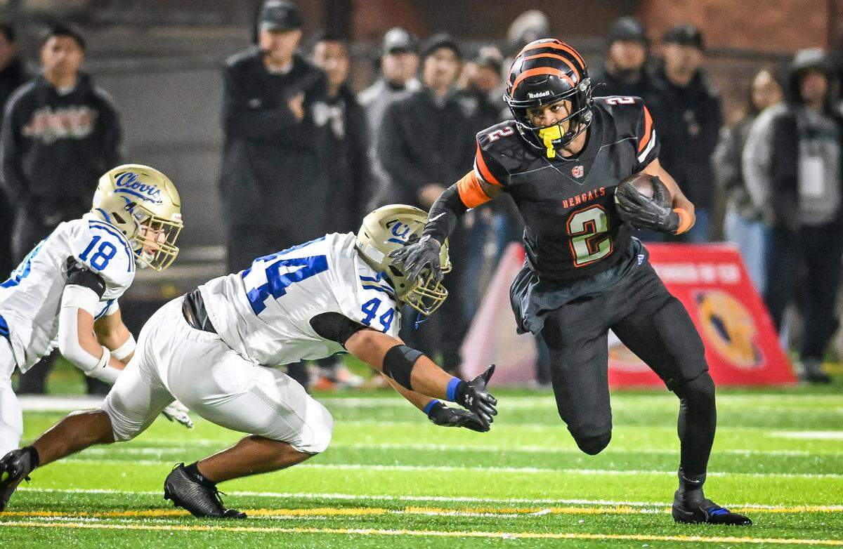 Central East's Brandon Smith turns the corner on Clovis defenders Brock Hartmann, left, and Caden Arsenault during their Central Section Division I-AA championship game at Deran Koligian Stadium on Friday, Nov. 21, 2025.