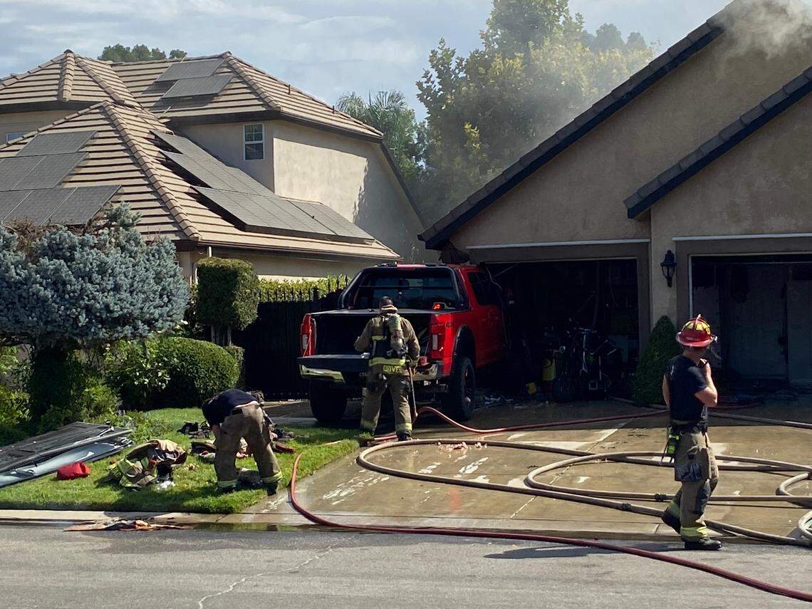Firefighters clean up after a truck smashed through the gate of a gated community and struck a house in north Fresno on Tuesday, Aug. 15, 2023.
