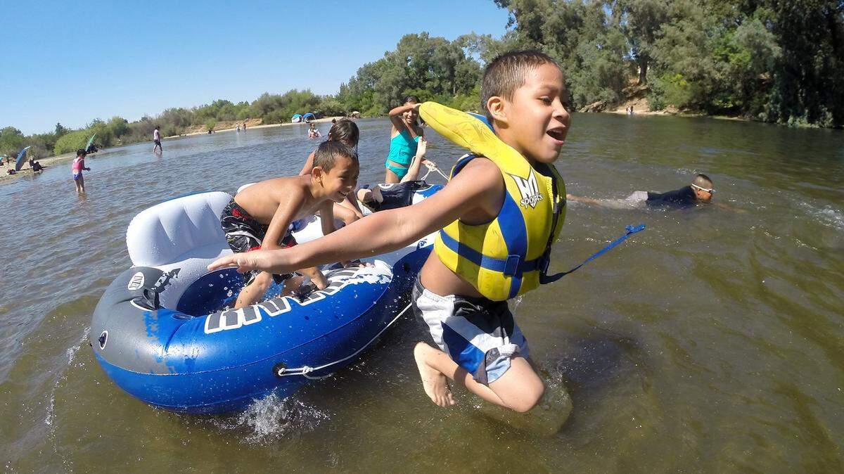 Rodrigo Borja, 7, of Dinuba, jumps off a raft while playing in the water at Reedley Beach in 2015. The river is currently closed by order of the sheriff.