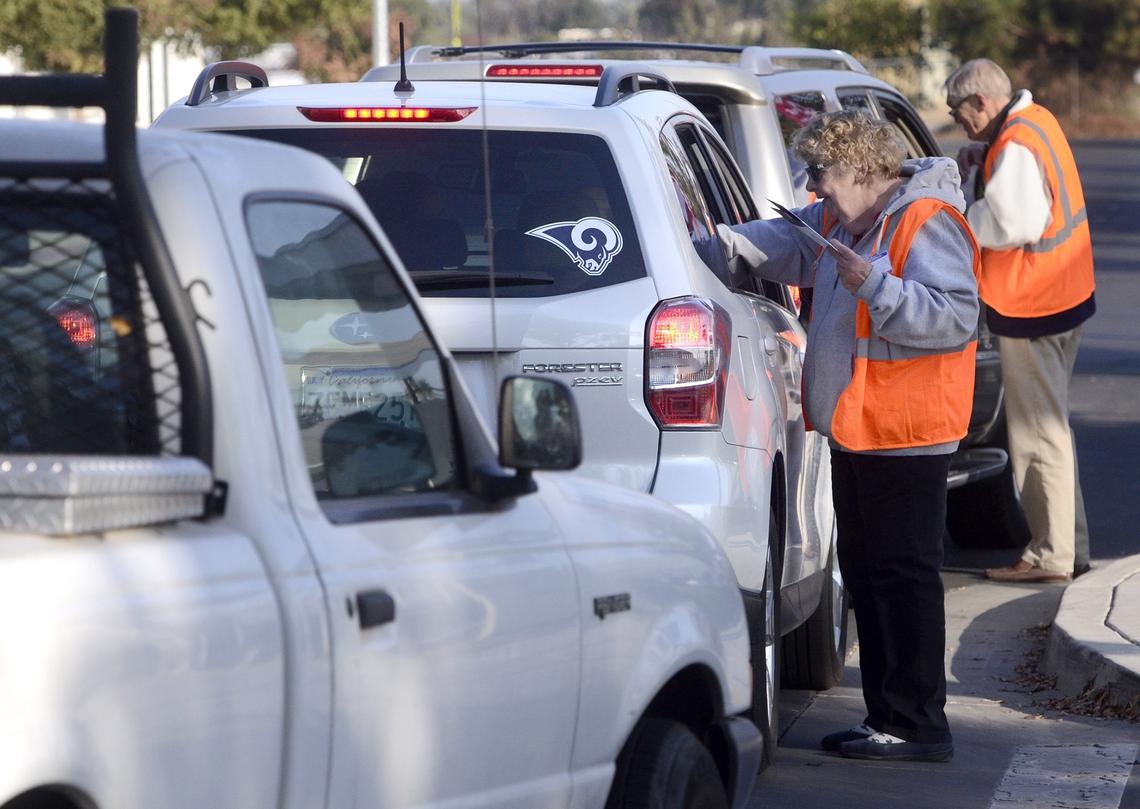 Election clerks Sharon Gomez, center, and Ken Warkentin, right, take ballots from motorists in the ballot drive-through at the Clovis Veterans Memorial District Hall, Tuesday morning, Nov. 6, 2018.