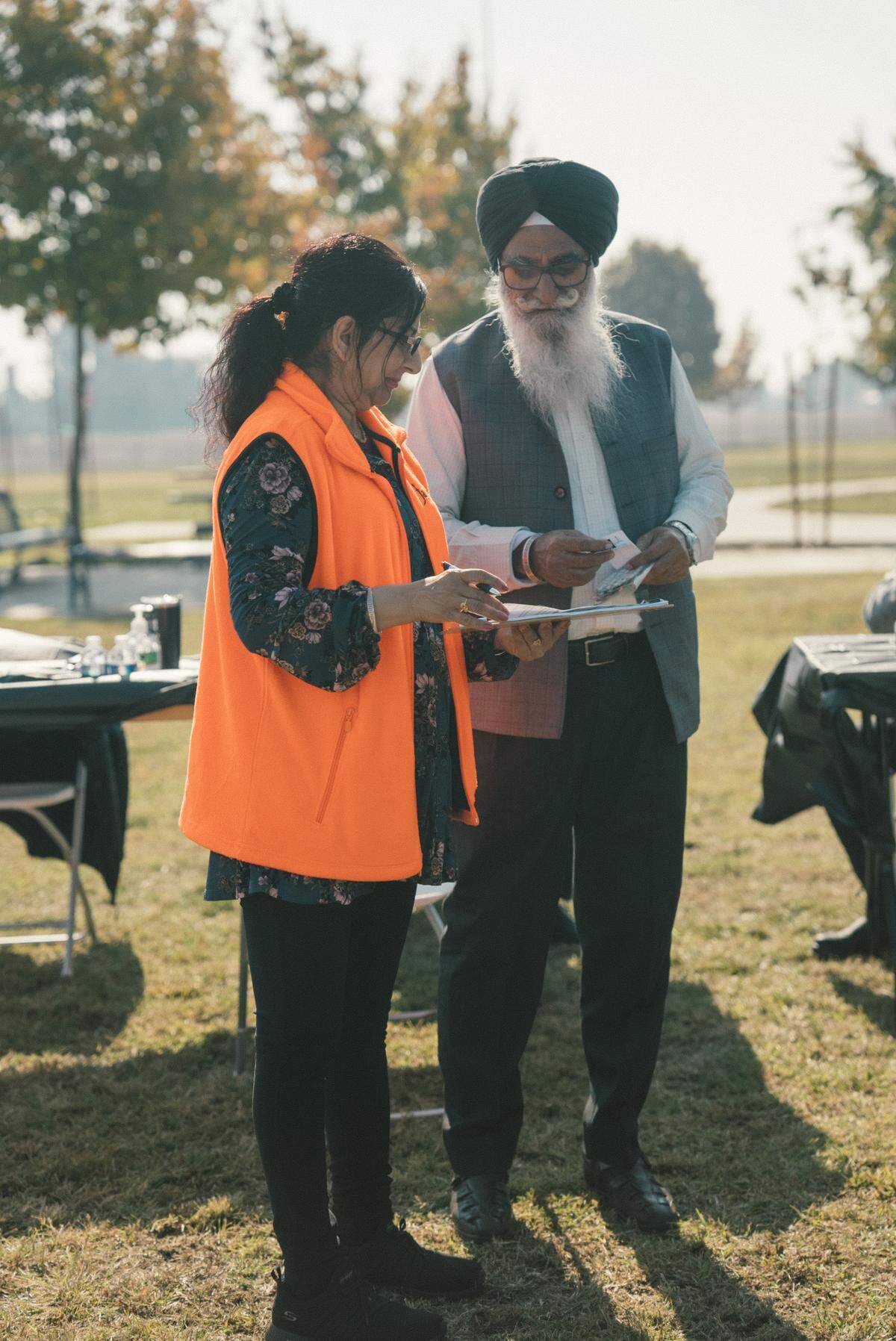 Harjit Kaur, a community health worker with the Jakara Movement, helps a Sikh community member register for a health clinic during a 2023 event at Jaswant Singh Khalra Neighborhood Park in Fresno.
