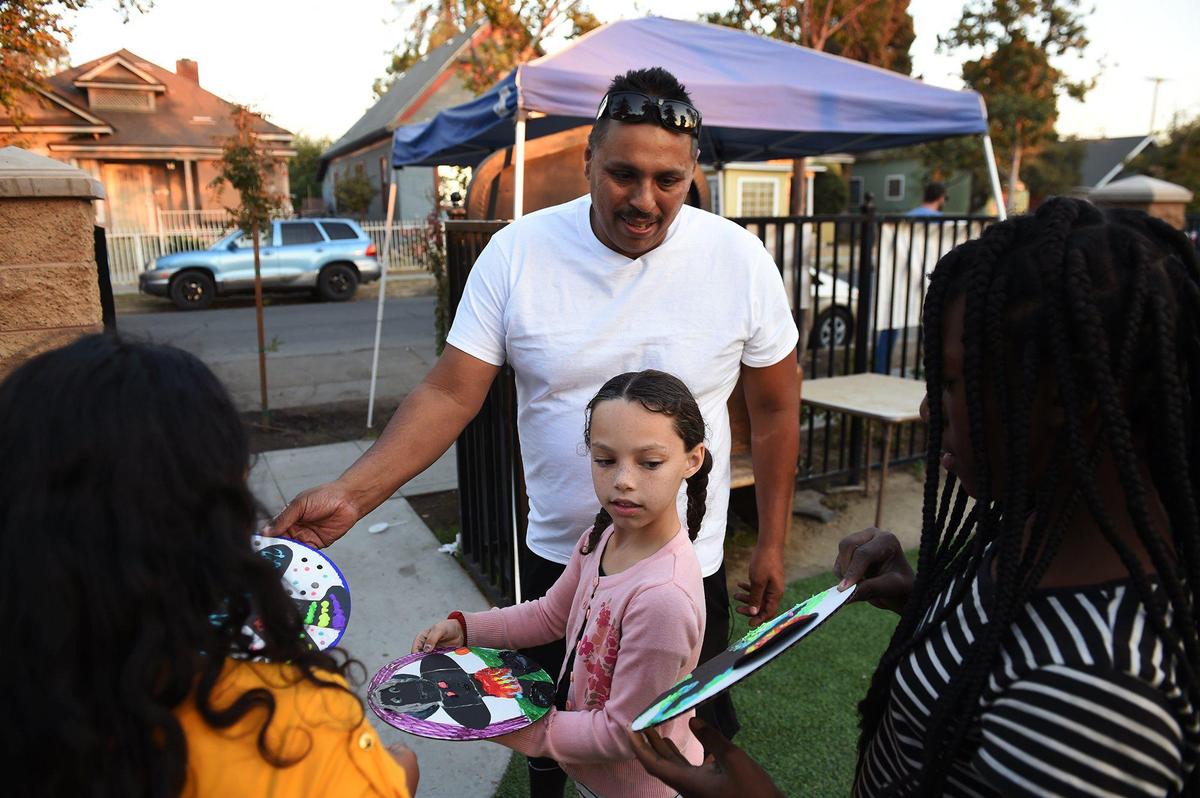 Oscar Rodriguez, top center, looks over artwork created by neighborhood children ay Martin Park in the Lowell neighborhood Tuesday, Oct. 29, 2019 in Fresno.