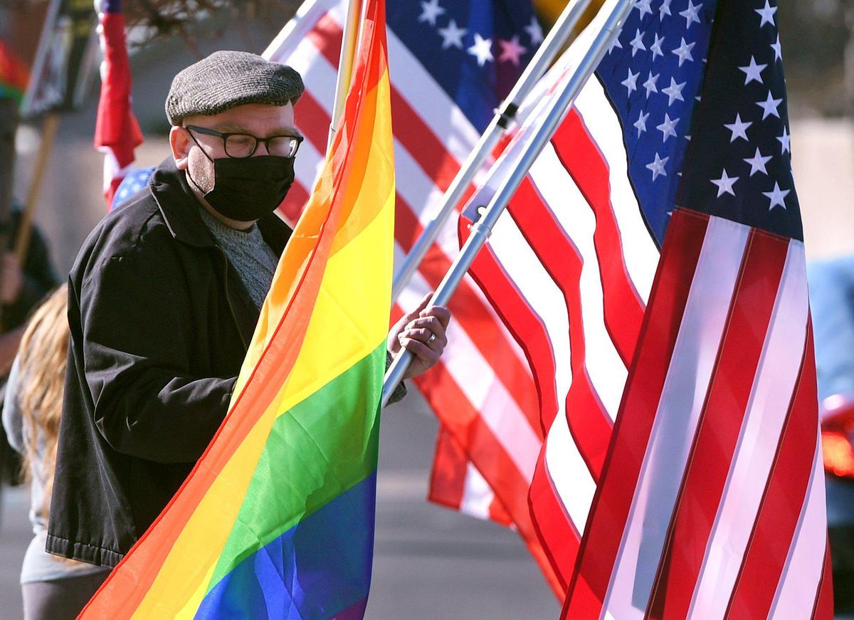 Jaguar Bennett holds bith a rainbow flag and an American flag with counter-protesters in the background across from the Tower Theatre protesting rezoning and the purchase of the theater by Adventure Church on Sunday morning, Feb. 21, 2021 in Fresno.