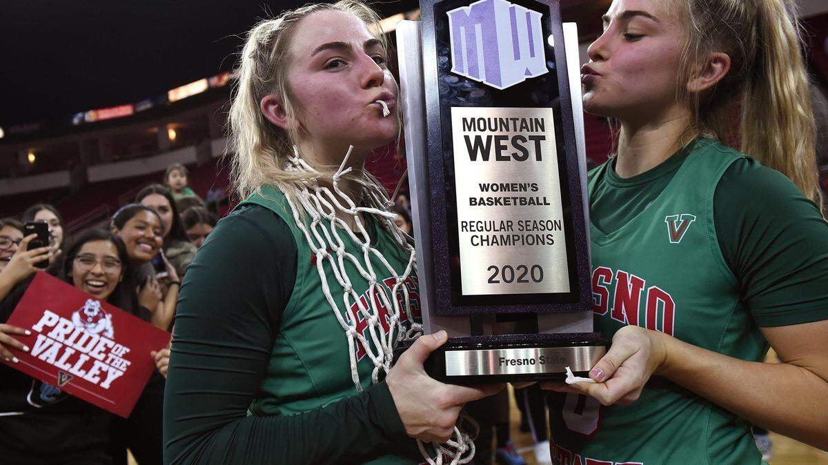 Fresno State freshman guards Haley Cavinder, left, and her sister Hanna Cavinder, right, pose with the Mountain West trophy after defeating San Jose State 78-76 Wednesday, Feb. 12, 2020 in Fresno.