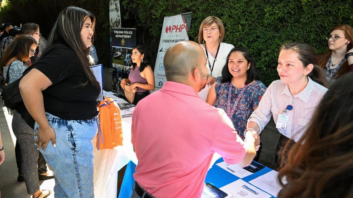 Job-seekers stop to speak to City of Fresno recruiters who were among dozens of area businesses and government agencies looking to hire during a job fair hosted by Workforce Connection and the City of Fresno in response to the laying off of 300 Fresno employees from Bitwise Industries, at Fresno City Hall on Friday, June 16. 2023.