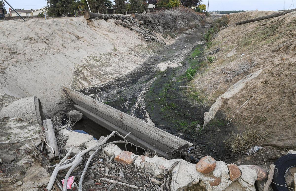 A drainage canal next to Kingsburg resident Doug Johnson’s property, shows remnants of a build up of black sludge which he says was dumped there by the Sun-Maid Raisin factory next door.