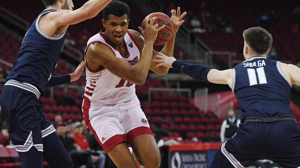 Fresno State forward Orlando Robinson attempts to drive past Utah State’s Brandon Horvath, left, and Max Shulga, right, in the first half of the Bulldogs’ 61-54 victory over the Aggies Tuesday night, Jan. 18, 2022 in Fresno.