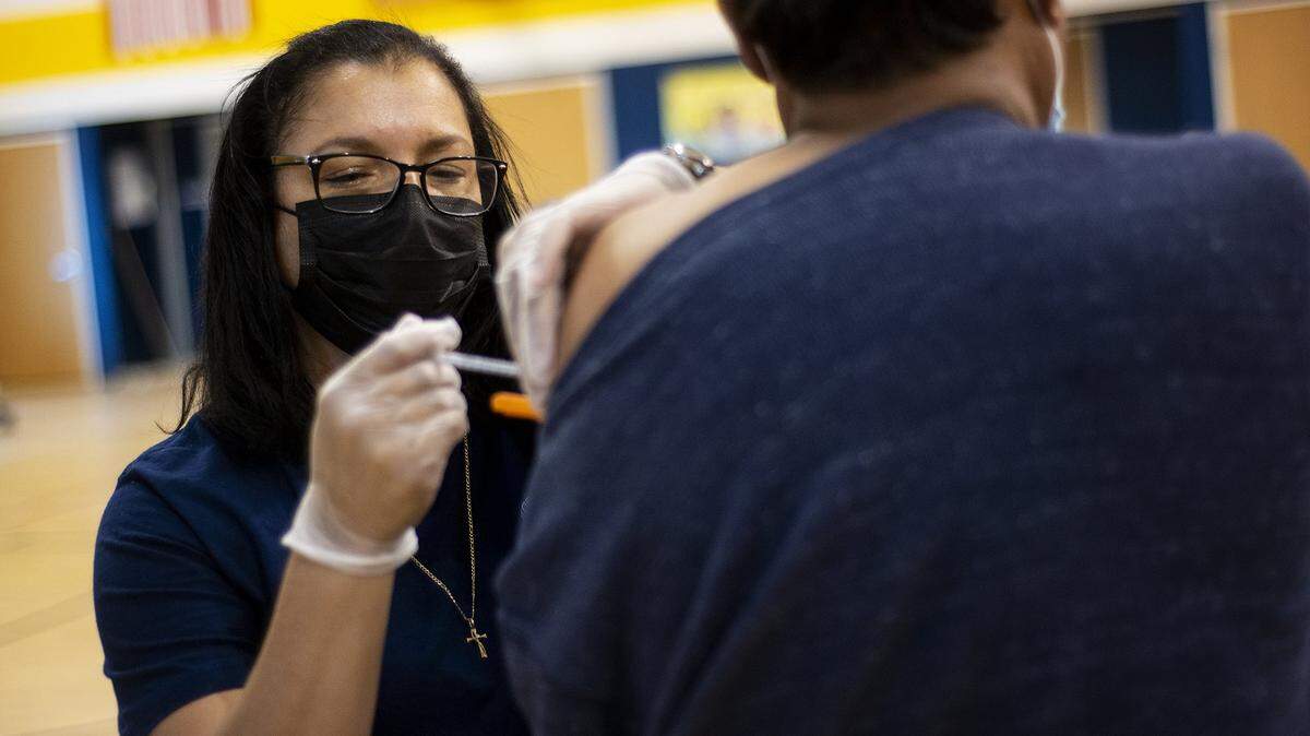 Registered nurse Julia Mercado administers a COVID-19 vaccine to a patient at a vaccination clinic inside the Cesar E. Chavez Middle School gymnasium in Planada, Calif., on Thursday, March 4, 2021.