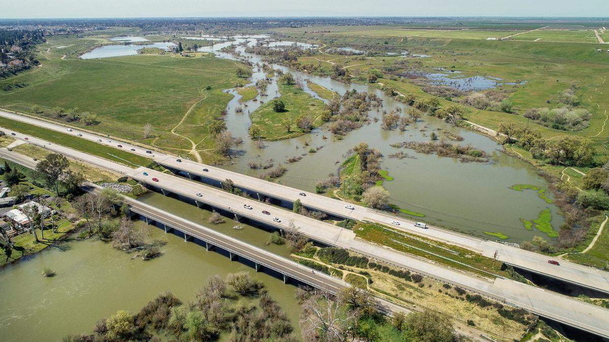 The swollen San Joaquin River meanders west at the Highway 41 bridge between Fresno and Madera counties as seen from this drone image on Wednesday, April 5, 2023. Releases from Friant Dam have been in excess of 8,000 cfs for weeks due to the heavy storms this year.