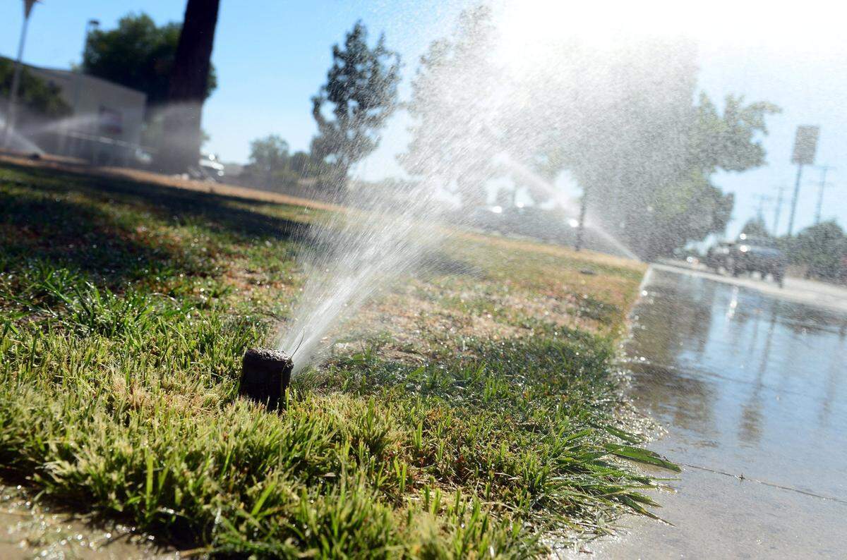 Sprinklers run on a grassy area in front of Eaton School in Fresno in this 2014 photo. Runoff is to be minimized during a drought.