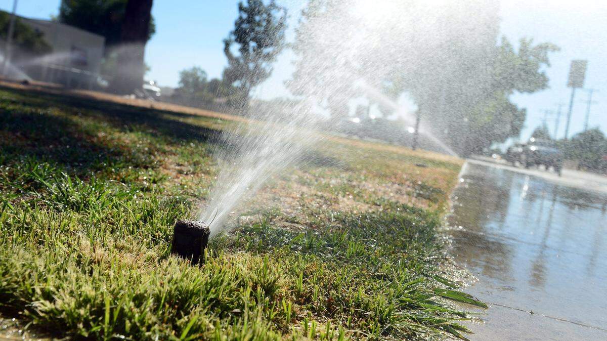 Sprinklers run on a grassy area in front of Eaton School in Fresno in this 2014 photo. Runoff is to be minimized during a drought.