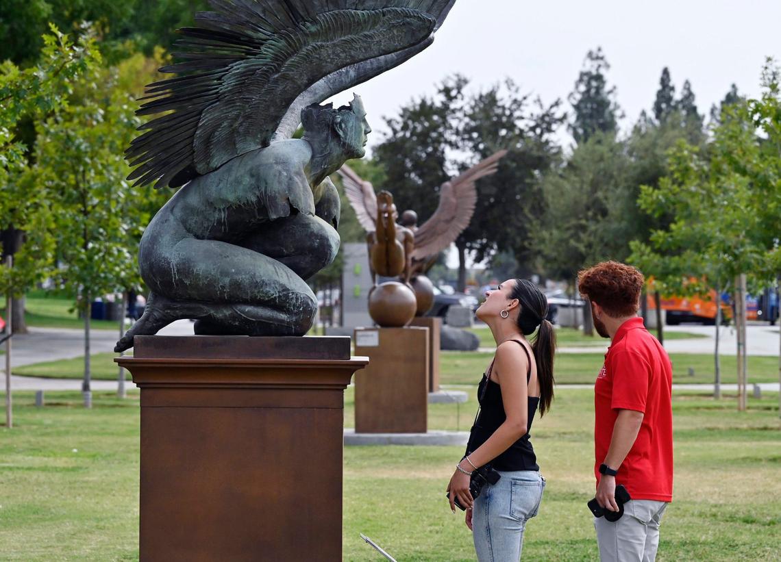 Sophia Sandoval, left, looks up to one of five bronze sculptures in the art installation titled “Wings of the City” by Mexican artist Jorge Marín as Zeferino Oshiro stands to the right Wednesday, Sept. 18, 2024 in Fresno. “Wings of the City” is now on display along Fresno State’s Maple Mall through August 2025 and is accessible to the public.