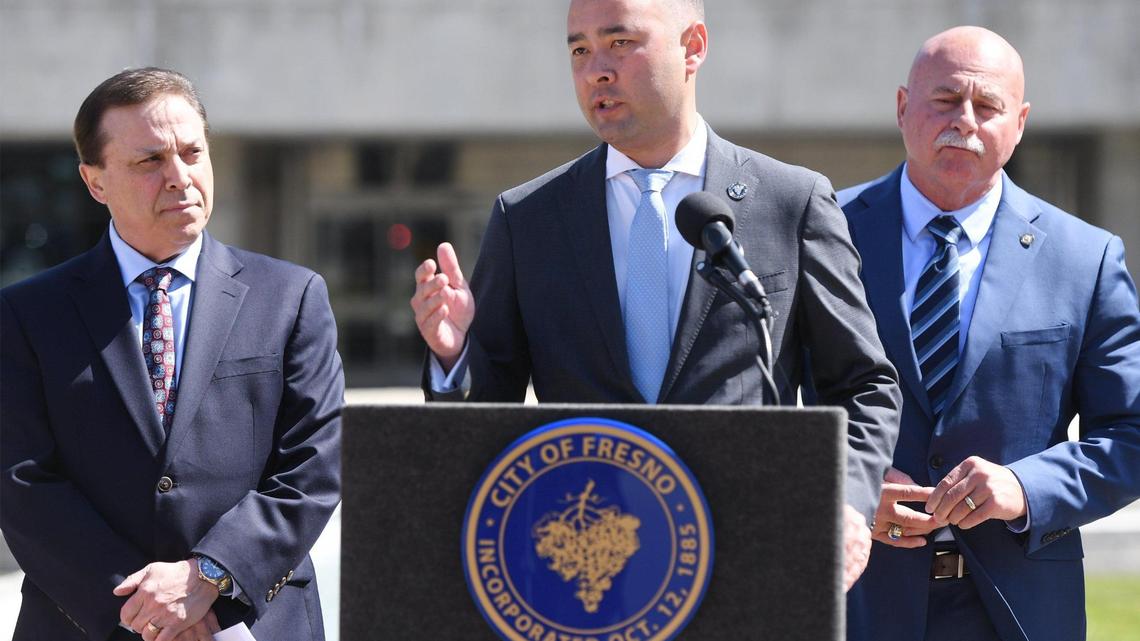 Fresno City Attorney Andrew Janz, center, with councilmember Garry Bredefeld, and Mayor Jerry Dyer, right, answers a question from the media about a proposed ordinance to go before the city council that would fine those who attend and watch as well as participate in any street racing, sideshow or other driving they called reckless, during a press conference in front of Fresno City Hall Wednesday, April 19, 2023 in Fresno. .