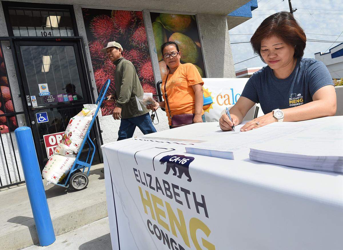 Congressional candidate Elizabeth Heng's aunt Kristie Cheng stations herself at a voter registration table outside the family's Rasmey Market, where Heng worked as a child.