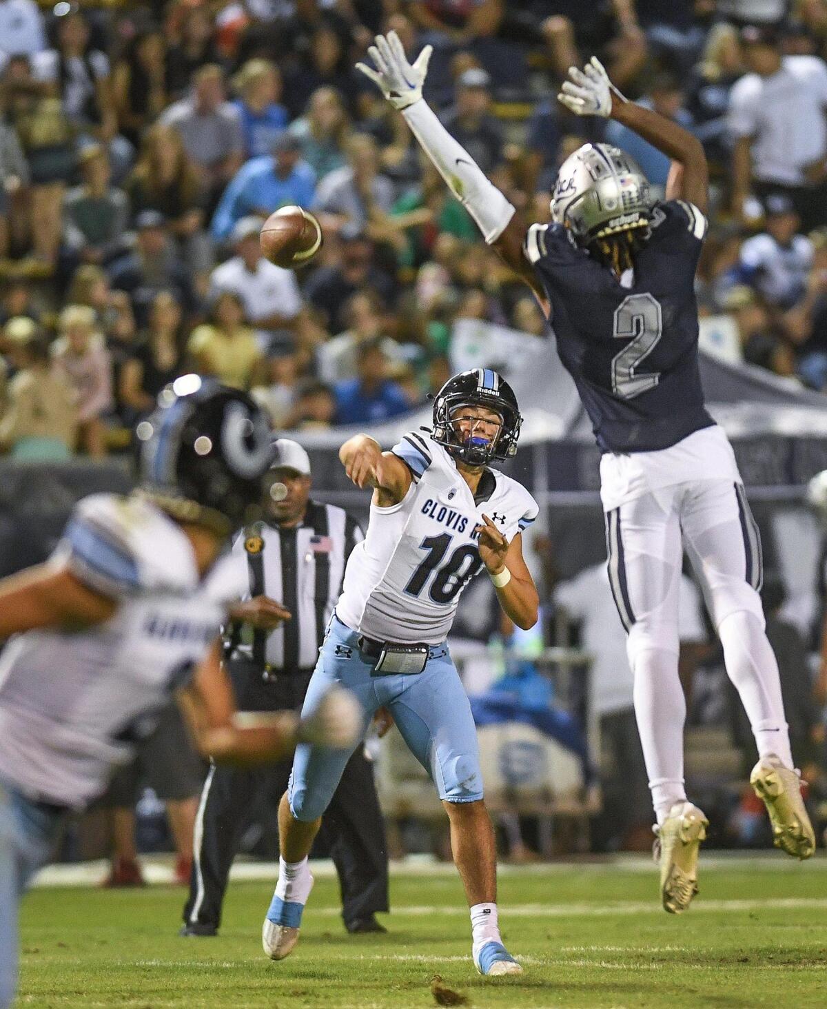 Clovis North quarterback Mario Cosma, center, passes to receiver Vincent Cordoba while getting pressure from Clovis East’s Harold Duvalls during their TRAC opener at Lamonica Stadium on Friday, Sept. 29, 2023.