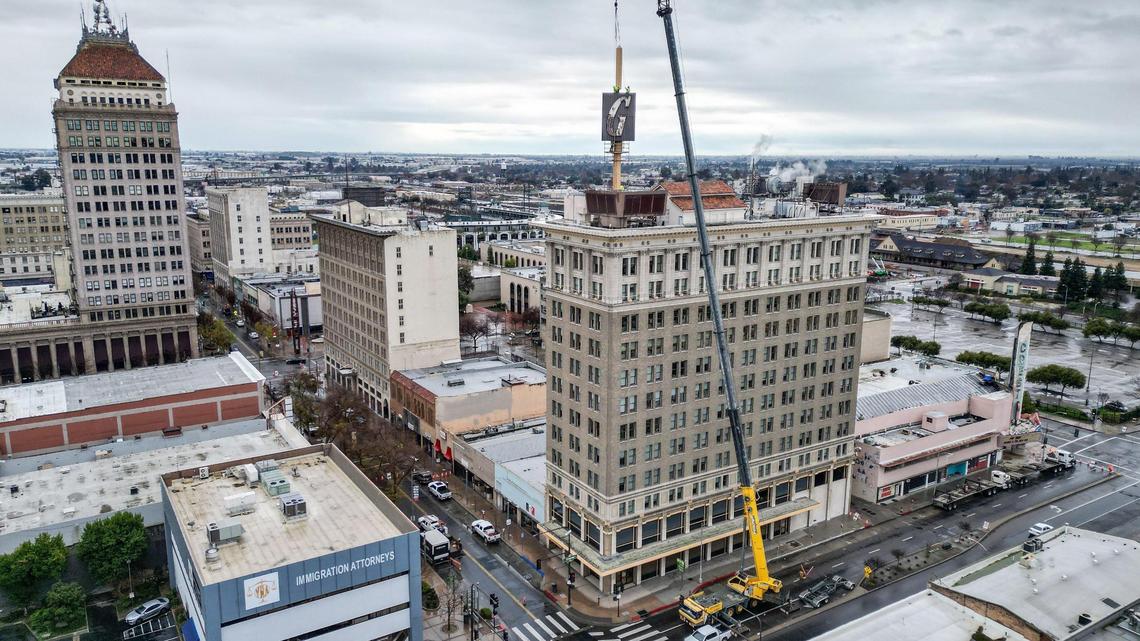 Workers attach crane cables to the G sign on top of the Guaratee Bank building, owned by the State Center Community College District, before attempting to lift it off its supports in downtown Fresno on Saturday, Jan. 20, 2024. The operation was halted due to issues with removing the 60-year-old sign from its supports and will be attempted again in a few weeks, SCCC officials said.