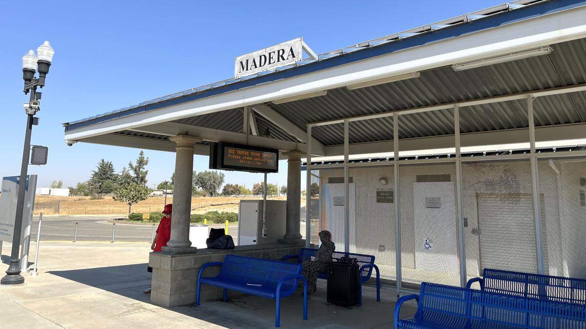 A pair of passengers wait in the shade under the canopy of the boarding platform at Madera’s Amtrak station on Tuesday, Sept. 24, 2024. The station at the northern fringe of Madera along the BNSF Railway tracks is set to be relocated about eight miles to the southeast in 2025.