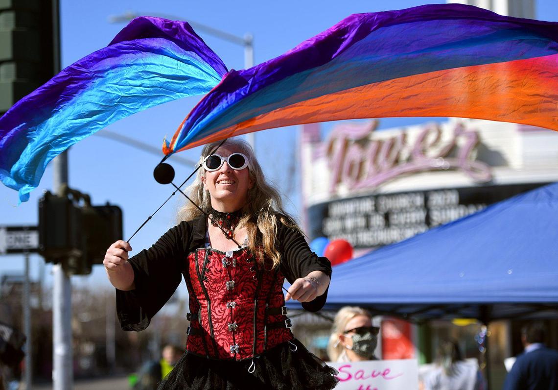 Tammy Eggert twirls banners as she stands on stilts as over 100 people gathered in a carrnival atmosphere across from the Tower Theatre to protest rezoning and the purchase of the theatre by Adventure Church Sunday morning, Feb. 21, 2021 in Fresno.
