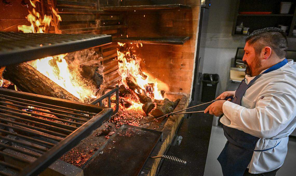 Grill cook Kevin New gets the wood embers hot for grilling dry-aged meats at Bulle, a new high-end restaurant in northwest Fresno on Tuesday, April 23, 2026. 