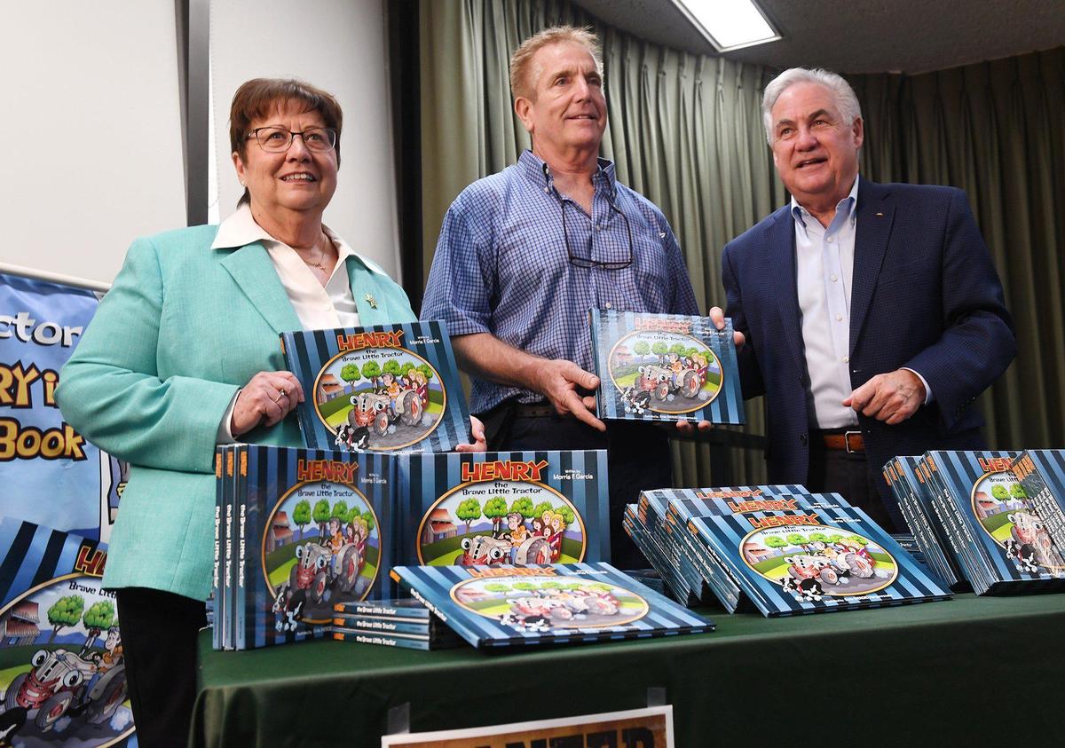 Fresno County Sheriff Margaret Mims and Assemblyman Jim Patterson stand alongside Kevin Garcia, center, who donated 100 copies of his late father Morris Garcia’s children’s book “Henry The Brave Little Tractor” to the Sheriff’s Reading Posse program Monday, Aug. 9, 2021 in Fresno.