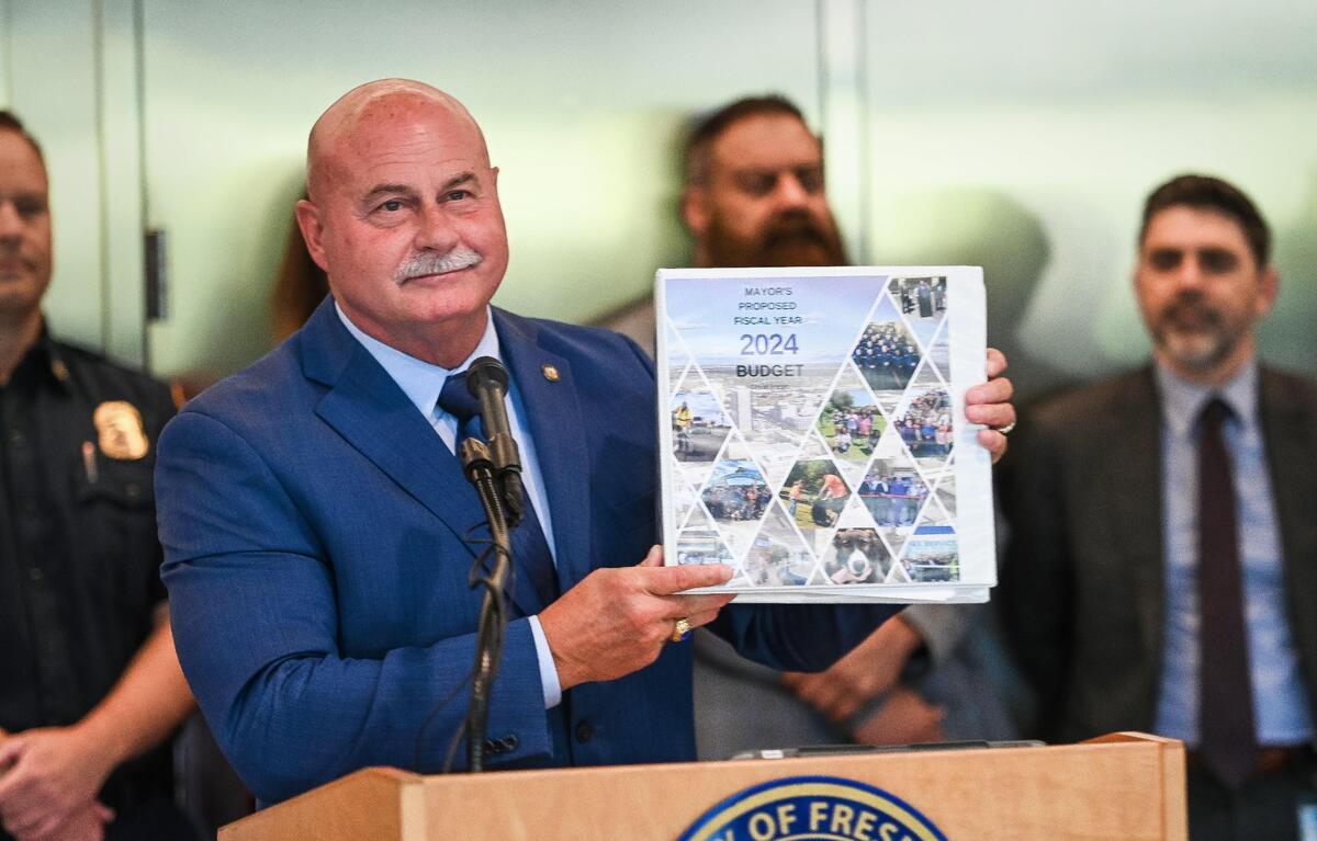 Mayor Jerry Dyer holds up a giant binder while presenting his fiscal year 2024 mayor’s budget during a news conference at Fresno City Hall on Thursday, May 18, 2023.