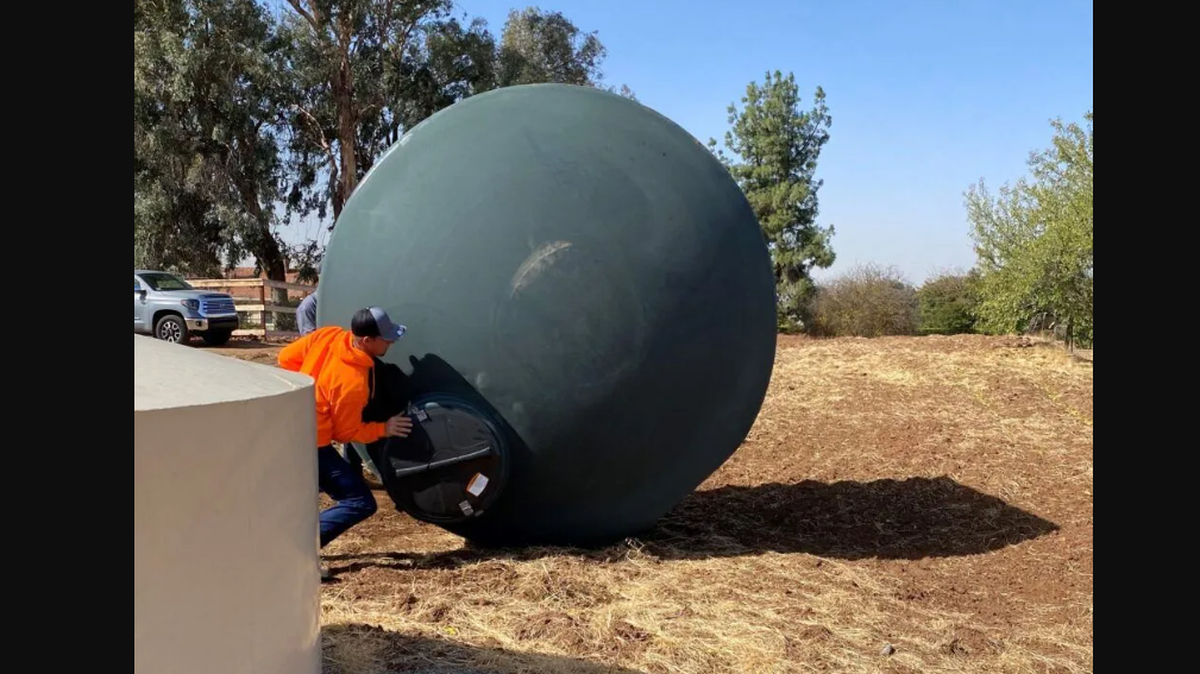 Trabajadores trasladan un tanque de almacenamiento de agua de 2,500 galones de Self-Help Enterprises a una propiedad al este de Clovis donde un pozo se había secado en 2021. Cientos de pozos domésticos se secaron ese verano.