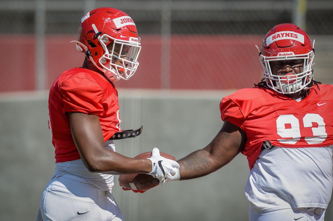 Fresno State defensive end Isaiah Johnson, left, takes the ball from teammate Jasad Haynes during drills at fall camp on Saturday, Aug. 10, 2019.