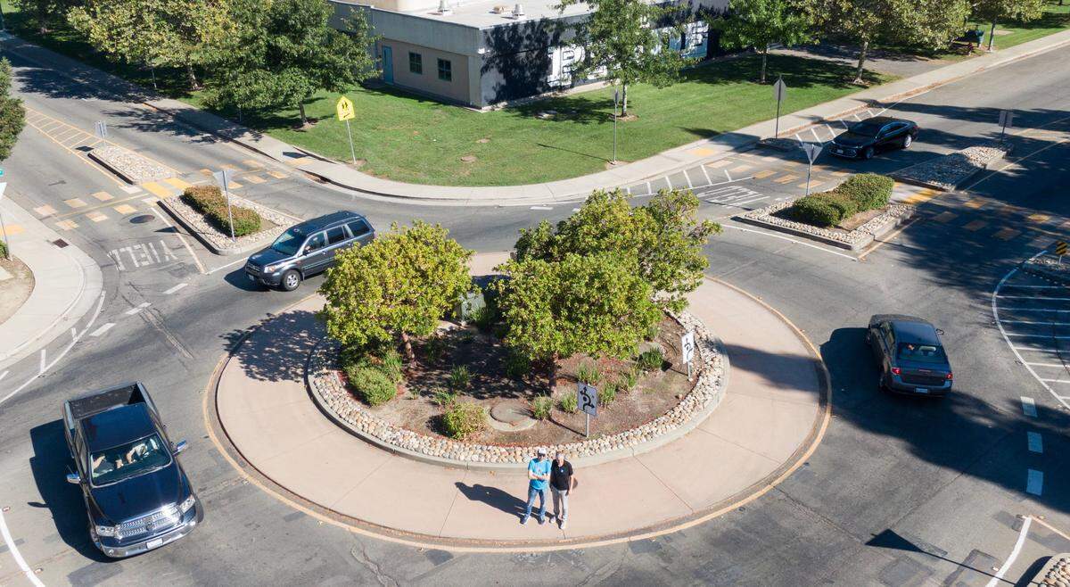Safer streets advocates Matt Malkin, left, and Jerry Champa stand for a picture Monday, Aug. 19, 2024, in the roundabout at the intersection of Orchard Lane and West River Drive in Sacramento’s South Natomas neighborhood, near Leroy Greene Academy.