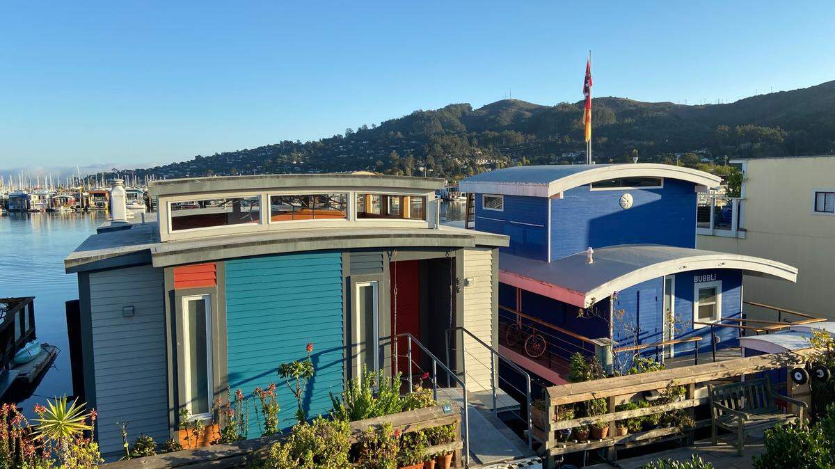 Two houseboats on the Issaquah Dock in Sausalito, California, as photographed from the balcony of another in October 2022. The Marin headlands can be seen in the upper right. San Francisco sits beyond the harbor and across the Bay in the lower left.