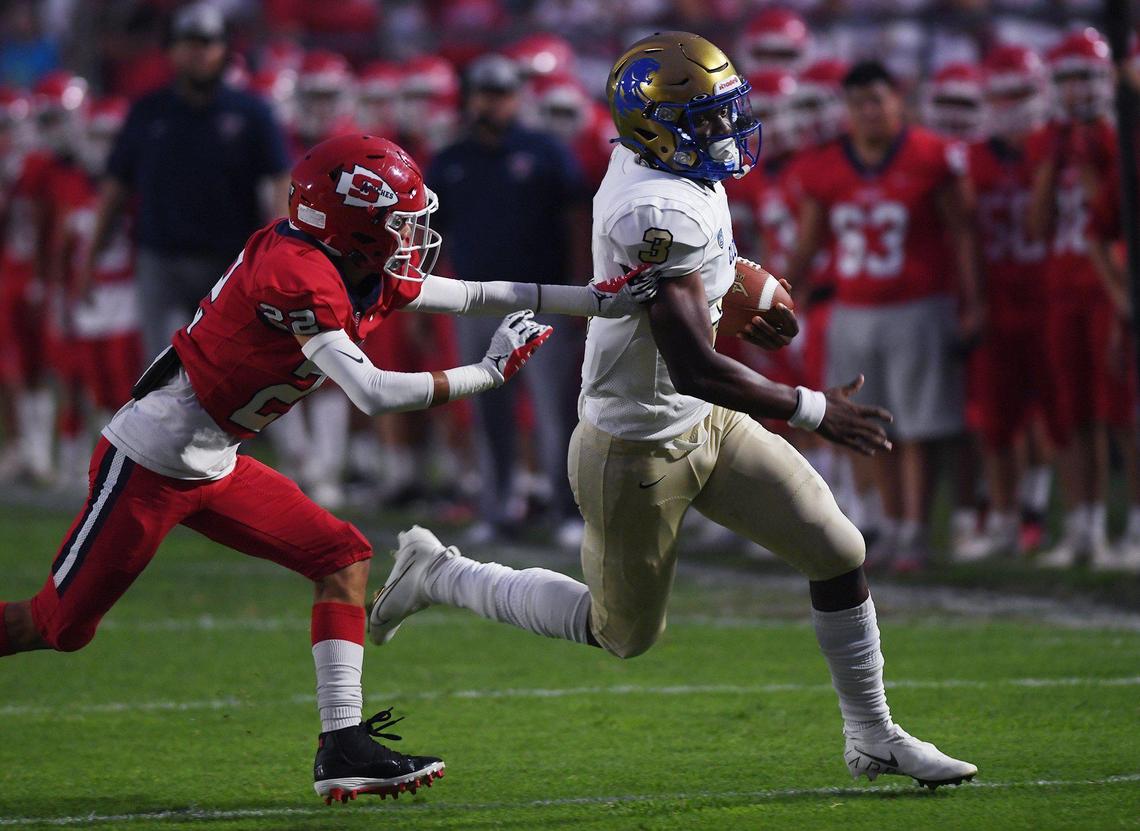 Clovis High quarterback Nate Johnson, right, outruns Sanger’s Markie Botello, left, in the season opener Friday, Aug. 20, 2021 in Sanger.