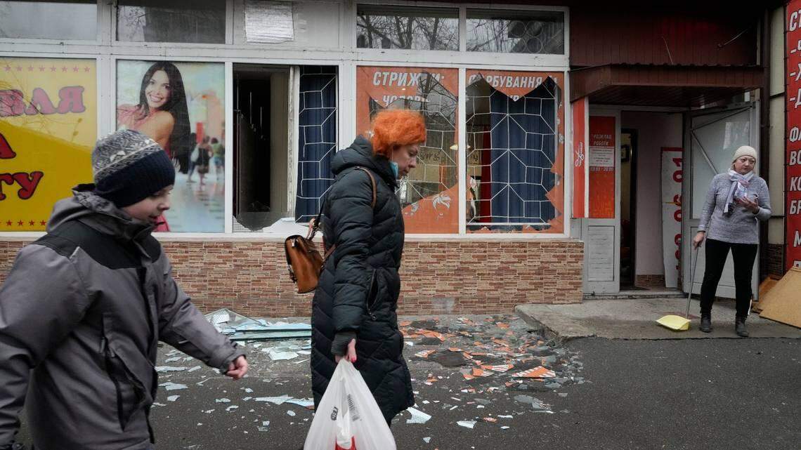 People walk past the aftermath of Russian shelling in the Ukrainian capital of Kyiv on Thursday, Feb. 24, 2022. As russian troops launched their anticipated attack on Ukraine, large explosions were heard before dawn in Kyiv, Kharkiv and Odesa