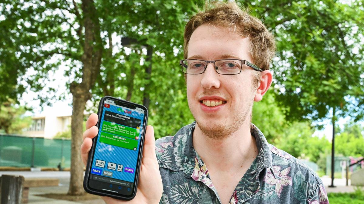Local game developer Dylan Woodbury shows his Wordle-inspired game app DisDat, a mobile phone game that challenges users to predict the correct answer to various current event topics in the news.