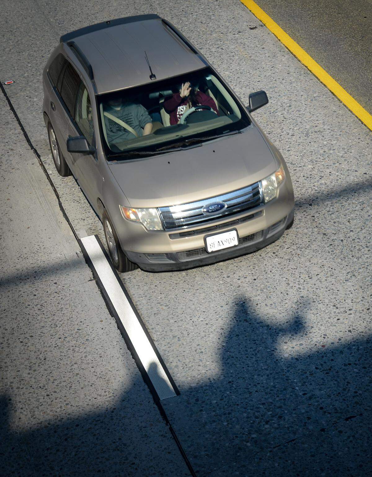 A driver waves back at Cheryl “Monique” Turks, 47, of Fresno, whose shadow appears on the ground below the Belmont Avenue overpass at Highway 41 in Fresno on Wednesday, Jan. 2, 2019.